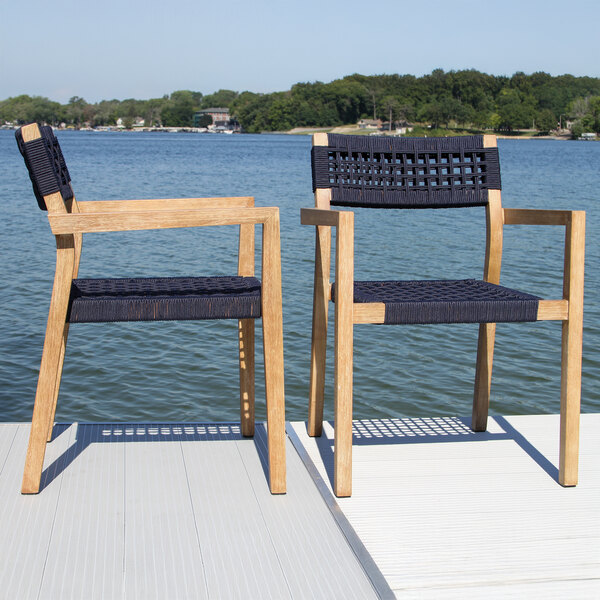 Two Outdoor Interiors blue rope and antique wash eucalyptus stackable chairs on a dock.