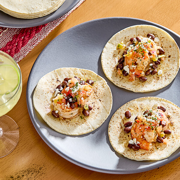 A Celia's white corn table tortilla with shrimp and beans on it.