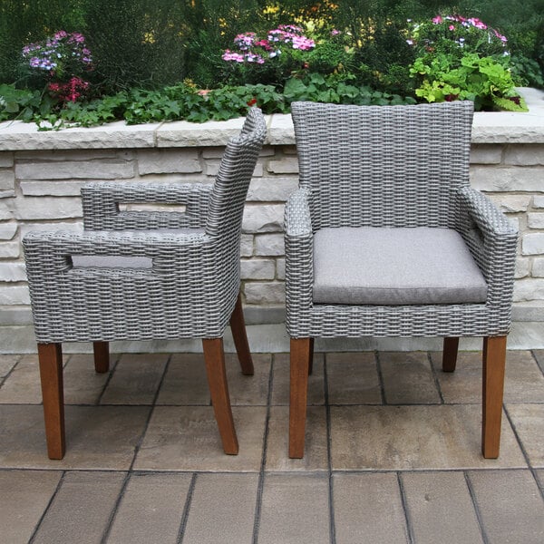 Two brown Umber and gray wicker Outdoor Interiors dining arm chairs on a patio.