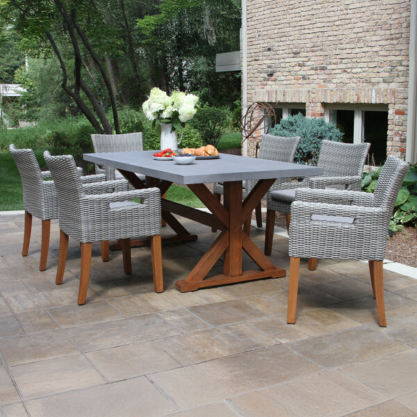 A close-up of an Outdoor Interiors brown umber Eucalyptus and gray wicker dining arm chair.