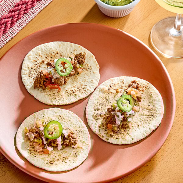 A plate of three tacos with Celia's flour tortillas filled with meat and jalapenos.