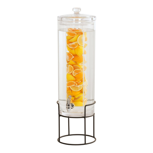 A Cal-Mil glass beverage dispenser with lemons inside on a black wire base.