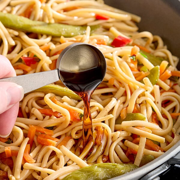 Golden Mountain Green Cap Seasoning Sauce being poured onto a bowl of noodles.