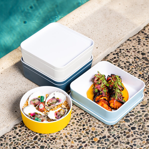 A white square Cal-Mil melamine bento box on a table with food inside.