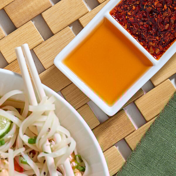 A bowl of noodles with red Pantai Pad Thai Sauce on a white background.