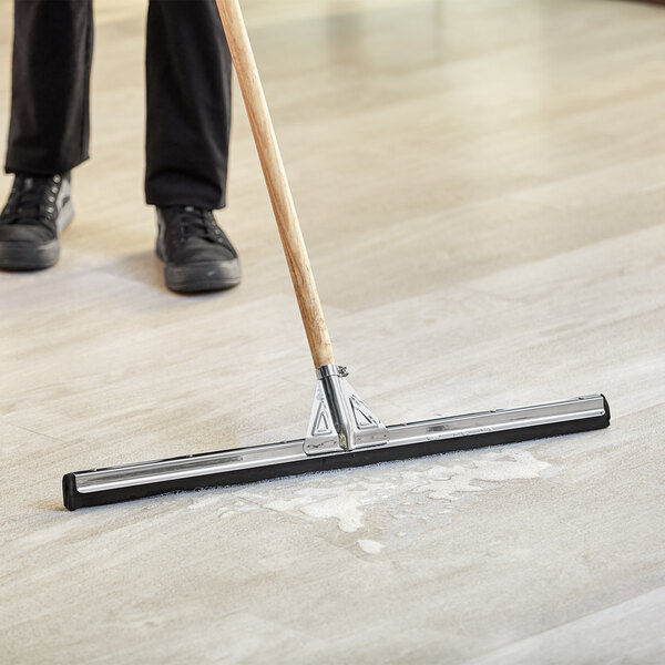 A person using a Lavex double neoprene floor squeegee to clean a floor.