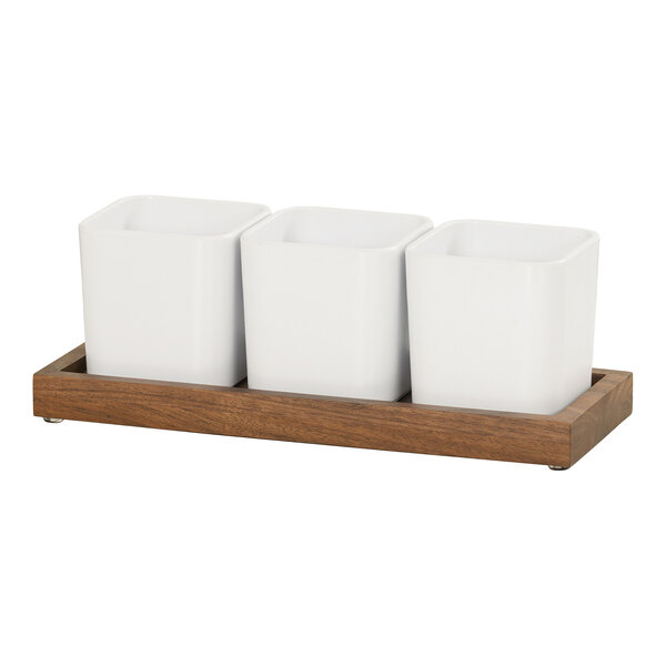 A wooden tray with 3 white square containers inside.