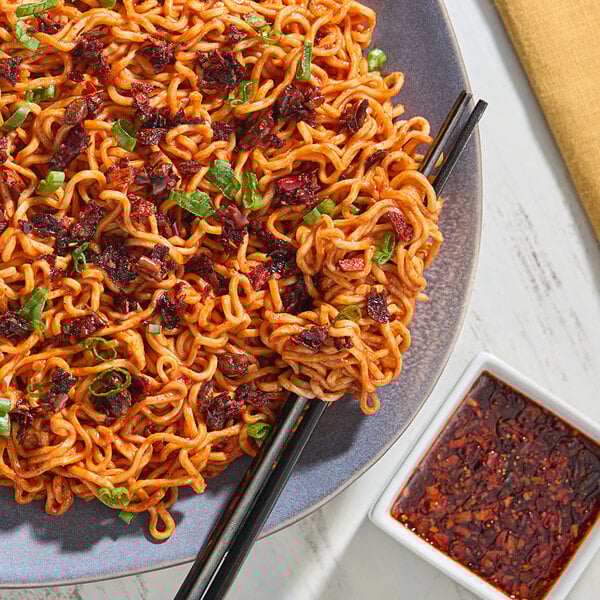 A plate of noodles with Lao Gan Ma Spicy Chili Crisp and chopsticks.