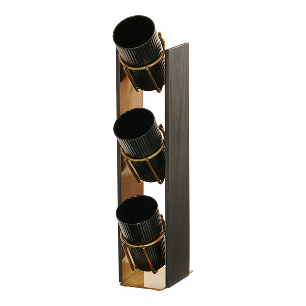 A black wood 3-tier display with brass metal cylinders holding coffee condiments.