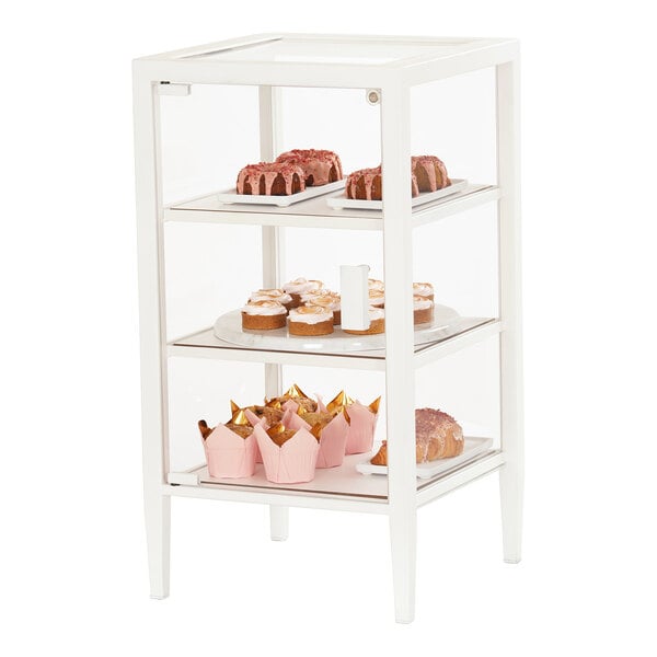 A white Cal-Mil bakery display case with glass shelves holding pastries and cupcakes.