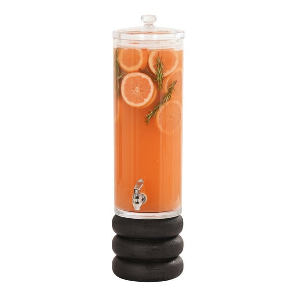 A Cal-Mil glass beverage dispenser filled with orange juice and orange slices on a black wood base.
