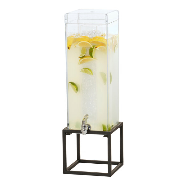 A Cal-Mil square drink dispenser with an ice chamber and black metal base full of water with lemon and lime slices.