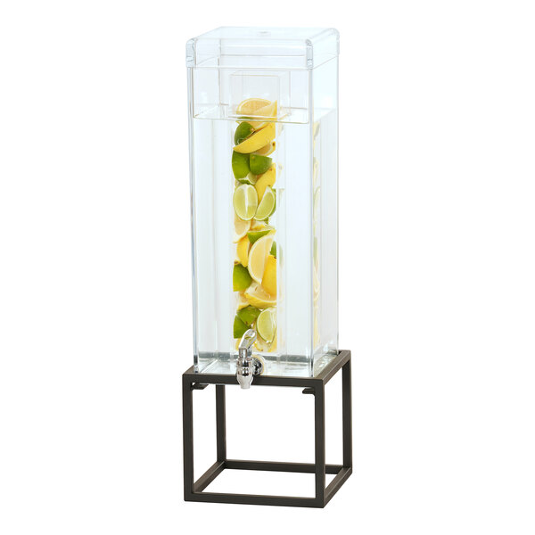 A Cal-Mil glass beverage dispenser with fruit slices in it on a black metal base.