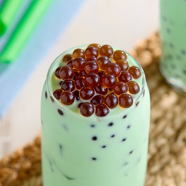 A glass of bubble tea with brown Fanale brown sugar popping boba on top.