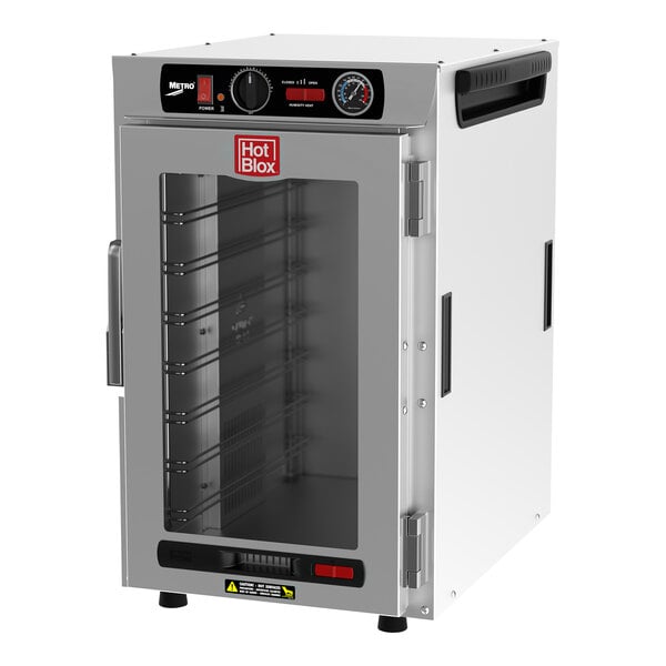 A white Metro heated holding cabinet with a clear door and black knobs holding trays.