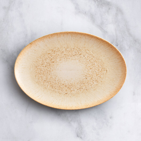 An Acopa Cape beige oval porcelain platter with brown trim on a marble surface.