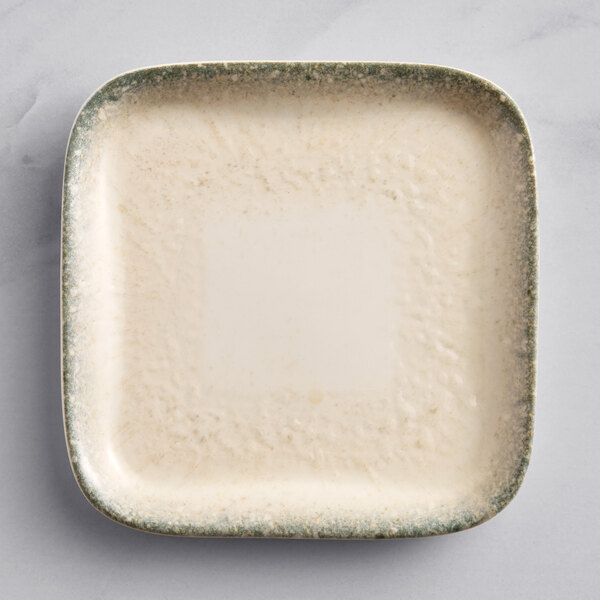A square white porcelain plate with a green rim.