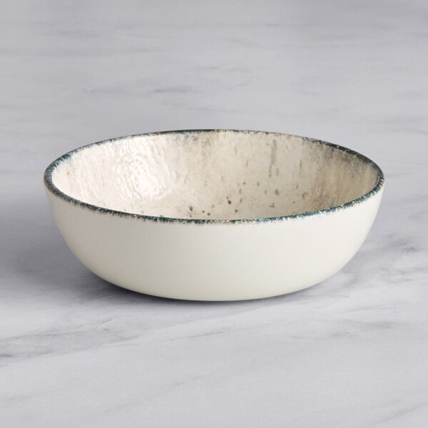 A white bowl with blue speckled rim on a marble surface.