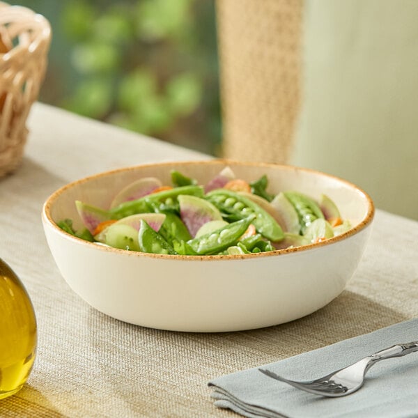 A round beige porcelain bowl filled with salad, placed on a table.
