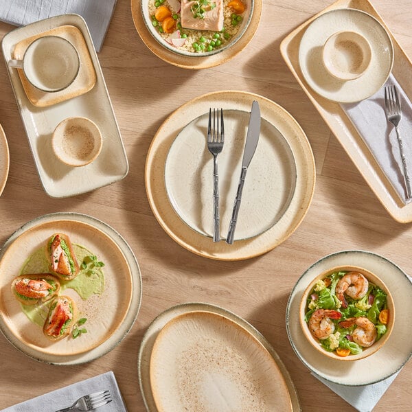 A set of beige porcelain bowls and plates arranged on a wooden table, some containing food and others empty.