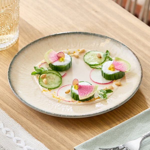 A round gray porcelain coupe plate with a light beige center, shown with a small appetizer arranged on it.