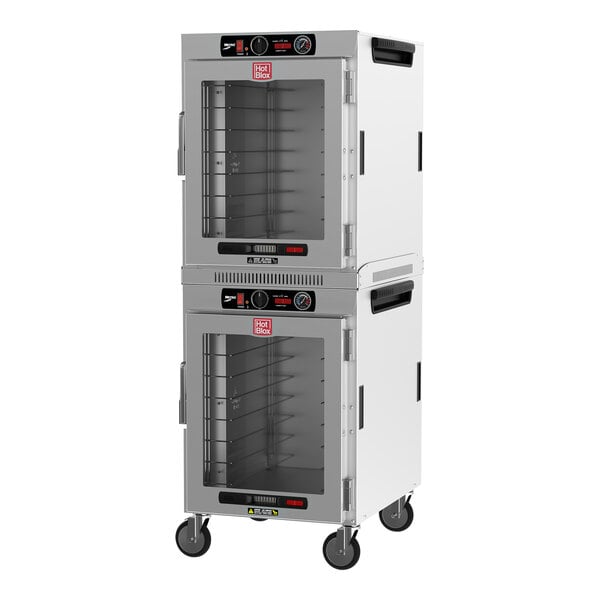 A white Metro heated holding cabinet with clear glass doors on wheels.