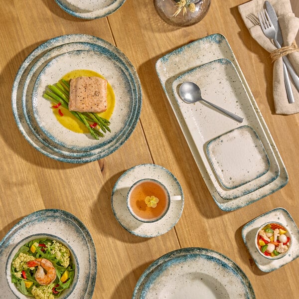 An oval gray porcelain platter with a speckled design, shown as part of a table setting.