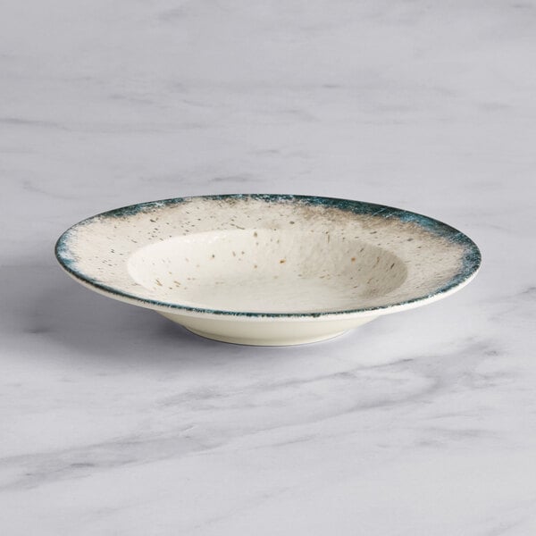 An Acopa Architect white porcelain bowl with blue specks.