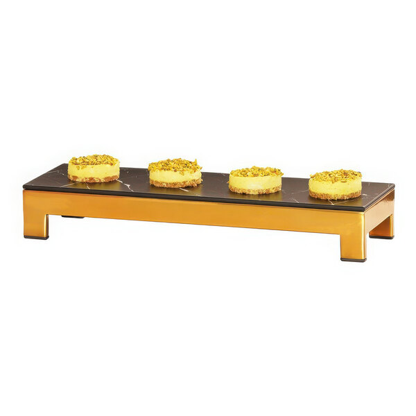 A Cal-Mil brass metal display riser with three cakes on it.
