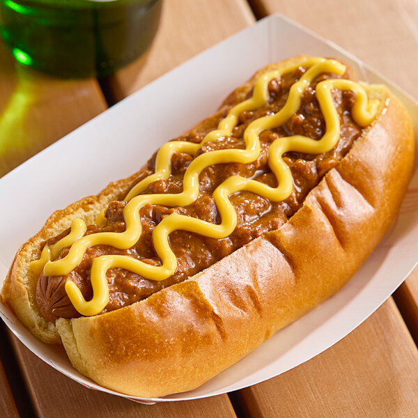 A hot dog with chili and Gehl's Mild Cheddar Cheese Sauce on top on a table in a stadium concession stand.
