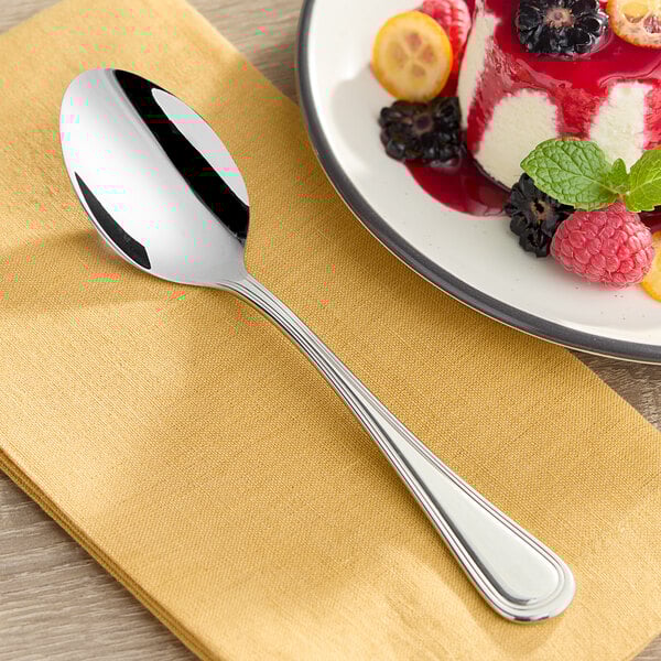 An Acopa Edgeworth stainless steel dessert spoon on a plate with fruit.