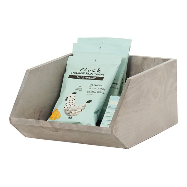 A gray wood merchandiser display bin holding several snack bags.