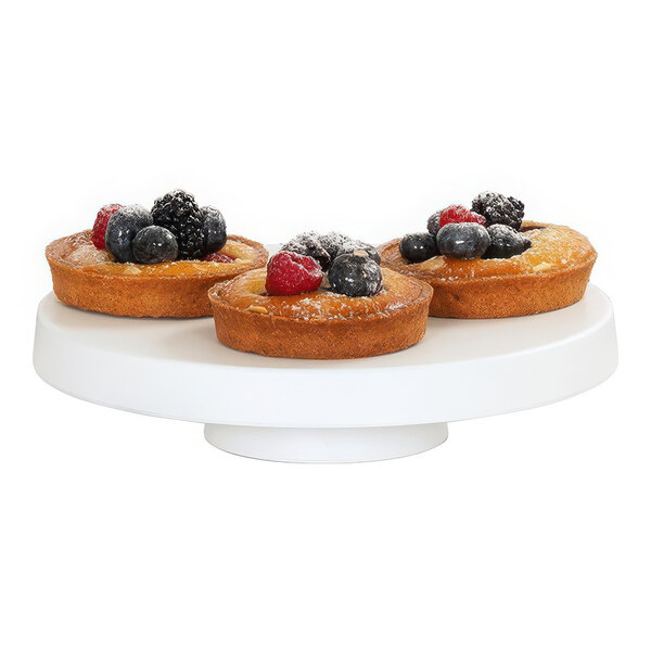 A group of fruit tarts on a white Cal-Mil melamine cake pedestal.