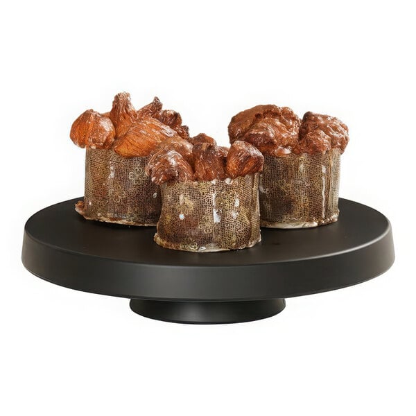 A group of brown cakes on a black Cal-Mil cake pedestal.