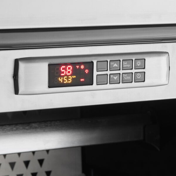 A stainless steel digital control panel on a dry aging meat curing cabinet displaying temperature and humidity settings.