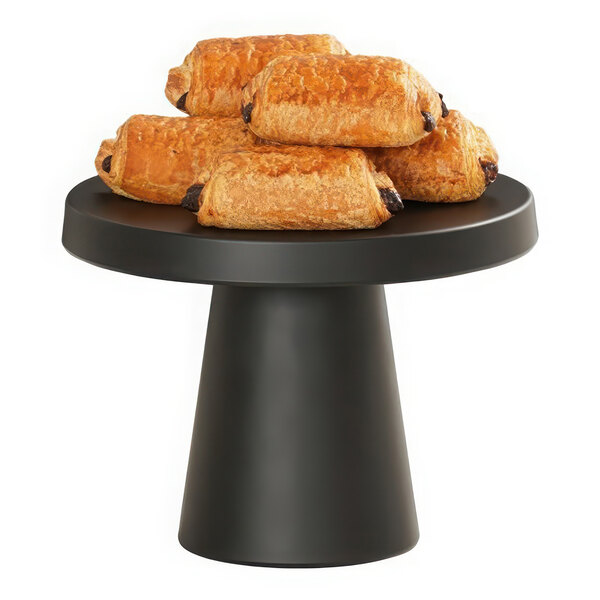 A black Cal-Mil round cake pedestal holding a pile of croissants on a table.