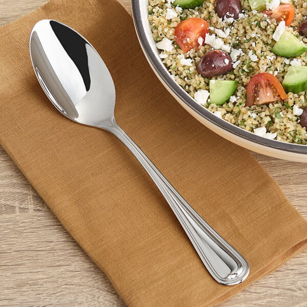 An Acopa Edgeworth stainless steel serving spoon in a bowl of food with vegetables.