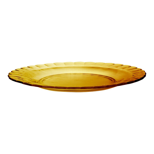 A close up of a yellow Duralex Picardie glass dessert plate with a scalloped edge.