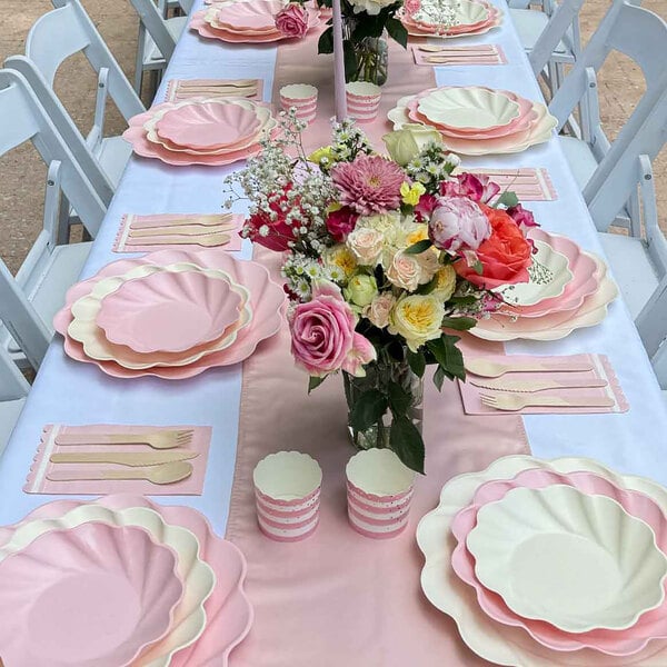A table set with Sophistiplate Simply Eco Blush Plant Fiber Dinner Plates and flowers.