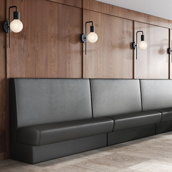 A long, black upholstered booth with a plain single back and a 36-inch high backrest, set against a wood-paneled wall.