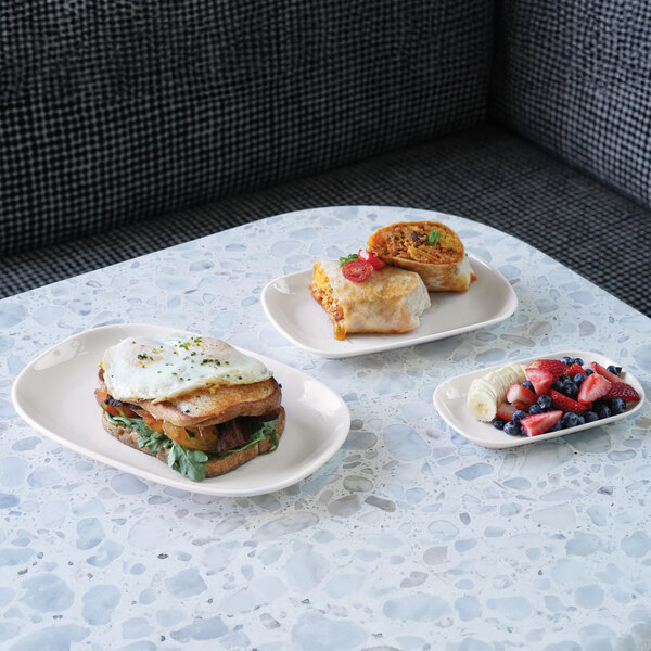 A Cal-Mil white oval raised rim melamine plate with food on it.