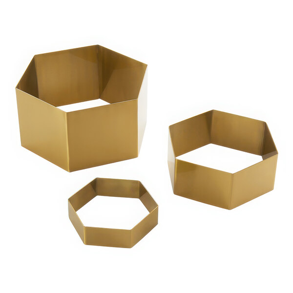 A group of three gold metal hexagon risers.
