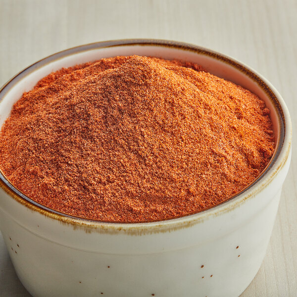 A bowl filled with orange-colored smokehouse popcorn seasoning powder.