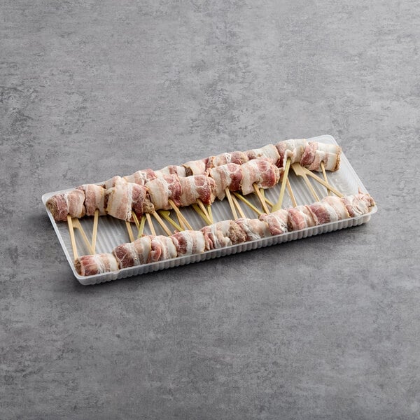 A tray of Cuisine Innovations bacon wrapped Wagyu and Gorgonzola skewers on sticks.