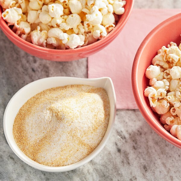 A bowl of Regal Spice savory garlic popcorn seasoning next to bowls of popcorn.