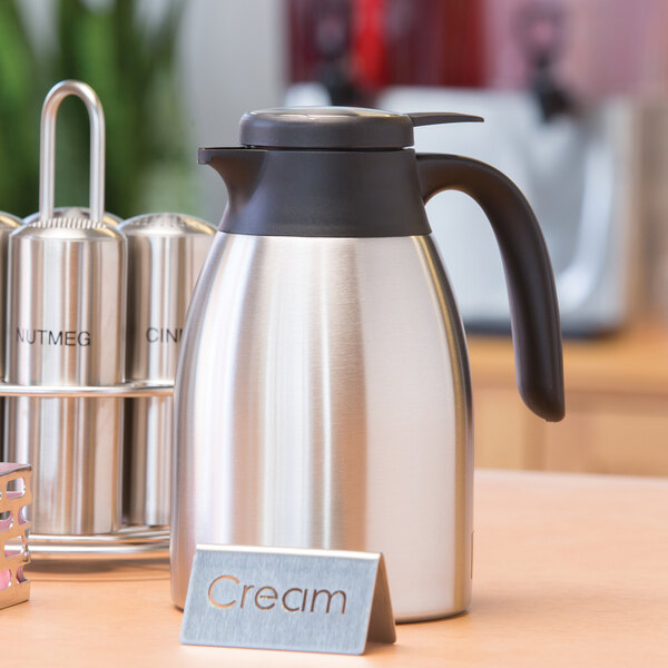 A close-up of a stainless steel Service Ideas coffee carafe on a counter.