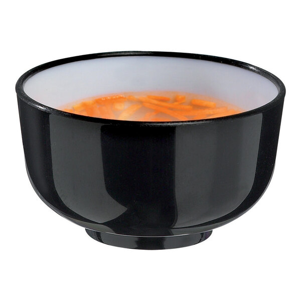 A black Solia Thai plastic bowl filled with orange soup with carrots.