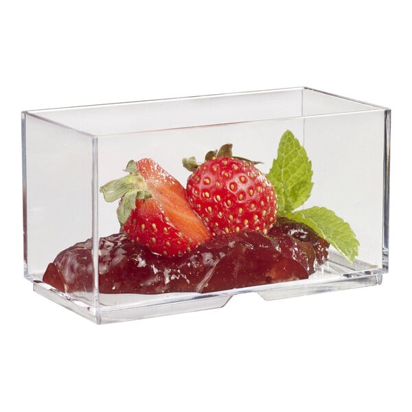 A Solia clear plastic mini dish filled with strawberries and mint on a table.