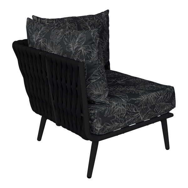 A BFM Seating black outdoor corner couch with a black and grey Sunbrella cushion and black pillows.