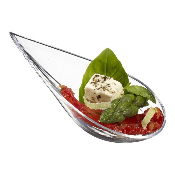A Solia clear plastic tasting spoon with vegetables and cheese on it.